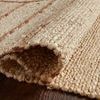 Rolled edge of the natural jute rug showing thickness and woven texture in braided pattern