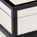 Close-up of corner joinery highlighting glossy black trim and smooth ivory lacquer surface