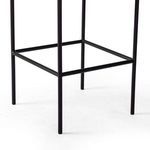 Detail of black iron frame and footrest bars on Benton Stool base