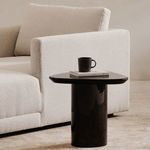Eden accent table styled beside a white upholstered sofa with a black mug and books on top