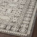 Angled close-up showing soft pile surface with intricate ivory and gray border patterns on wooden floor
