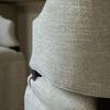 Close-up of beige textured fabric and elongated back opening with dark wood accent on Brewer chair