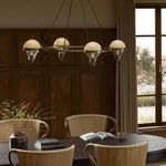 Hockley chandelier hanging above dark wood dining table in room with wood panel walls and window light
