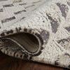 Rolled edge detail showing the thick pile and looped texture of a patterned rug in beige and dark brown