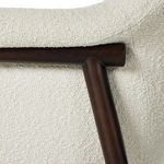 Detail view of wood frame joint at backrest corner with cream bouclé fabric