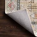 Close-up of Skye Gold Blush rug corner flipped up showing stitched edge and low pile polyester texture over dark wood floor