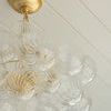 Side view showing layered arrangement of clear glass orbs around gold metal supporting structure