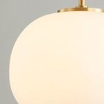 Close-up of illuminated white glass globe with a polished brass finish version of the pendant