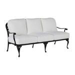 Three-seat outdoor sofa angled showing white cushions on black aluminum base with curled armrest