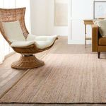Rosier rug in living room with wicker chair and beige cushions against white paneled wall