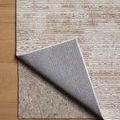 Corner of Townes Sand Beige rug lifted to reveal revers side and thick natural fiber rug pad underneath