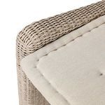 Close-up on corner edge of banquette showing rounded rattan frame and fabric cushion corner