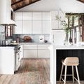 Long runner style rug in white modern kitchen with wooden ceiling beams and barstool