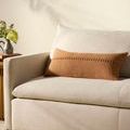 Harvey Orange Pillow styled on cream fabric sofa with neutral room background and side table