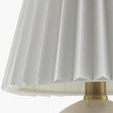 Close-up of white pleated linen lampshade with brass fixture