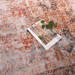 Close-up showing rug surface with glass vase and folded magazine on rust and navy patterned area