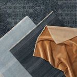 Multiple folded rugs layered, showing color variations including dark blue, light blue, and tan