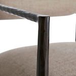 Close-up of hand-forged black iron armrest with textured pewter seat in background