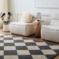 Isaac Charcoal Handmade Rug laid flat in a bright living room setting with cream lounge chairs and a wooden side table