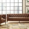 Living room scene with Nicolla armchair beside tufted sofa, modern art, and floor lamp