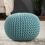 Spectrum Pouf in aqua shown in living room setting on rug with sofa and plant in background