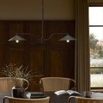 Chandelier installed above a dining table in a wooden paneled room with beige curtains and natural light