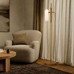 Lamp illuminated beside textured beige armchair and wooden table in softly lit living room setting