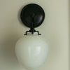 Front view of the sconce showing glossy white glass against a muted wall
