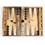 Backgammon board open on round wooden coffee table in natural light room with modern decor