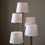 Close-up of four lit lampshades on bronze arms with warm ambient light in room