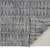 Back corner of rug flipped to show underside texture and woven construction with fringe