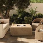 Donovan Outdoor Fire Table shown lit in patio setting surrounded by beige sofa and wicker chairs