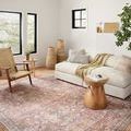 Adrian Rust rug styled in bright living room with beige sofa, woven chair, wooden side tables, and natural light