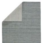 Back side of the rug flipped over, revealing a tightly woven light gray and blue striped pattern