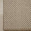 Top view of rug placed on floor highlighting corner with fringed edges and clear checkered weaving.