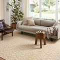 Noelle Ivory Gold Rug styled in bright living room with sofa, chair, wooden side table, and plants