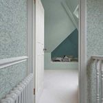 Salix Leaves wallpaper installed on hallway walls showing pattern in room context with white door and radiator