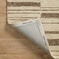 Close-up of rug corner flipped to show backing labeled with designer and brand names.