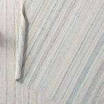 Textured back side of the rug showing the light blue and ivory threads and subtle wave pattern