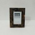 Frame standing upright against plain white wall on smooth white surface, highlighting its deep textured horn finish