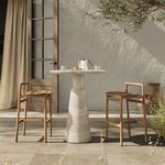 Outdoor bar table styled on patio between two wooden bar stools with teapot and glasses