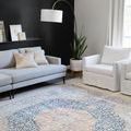 Layla rug displayed in modern living room with gray sofa, white armchair, black accent wall, and indoor plant