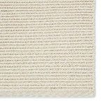 Close-up detail of braided rug surface focusing on woven texture and color variation between beige and ivory yarns