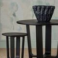 Close-up environmental shot focusing on vase on table with stool near wall
