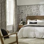 Esther Wallpaper applied on bedroom walls with natural light, rattan bed frame, and neutral soft furnishings