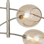 Close-up of two champagne glass globes on curved nickel arms with lit filament bulbs inside