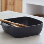 Side angle view of seed grey stoneware square baker with wooden spoons inside