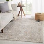 Rug styled in a bright room under a light gray sofa with wood side table and pouf