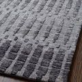 Close diagonal view of rug edge highlighting subtle color variation and texture on dark wood floor
