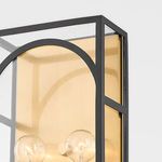 Side angle of wall sconce showing black metal frame with glass and gold interior